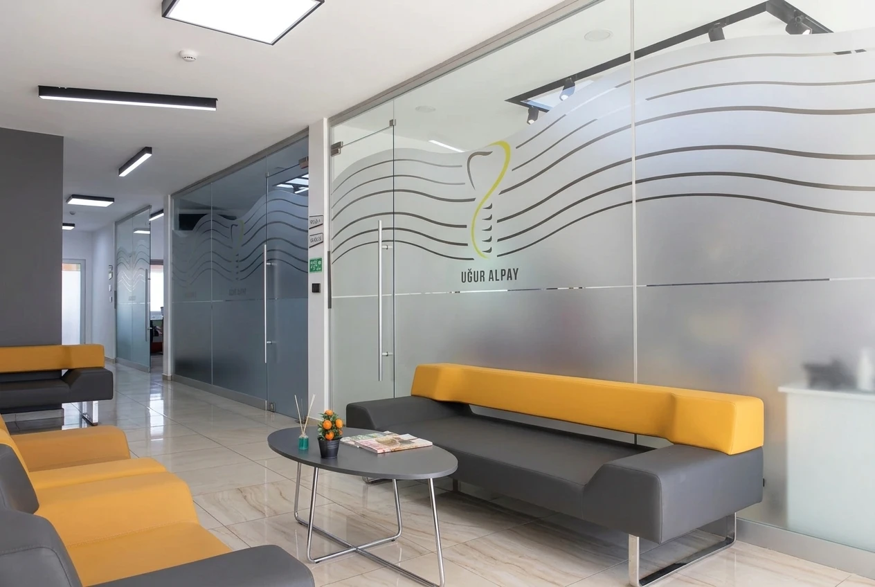 Bekleme salonu, sarı oturma bankı ve Klinik 1 / Klinik 2 yönlendirmesi
