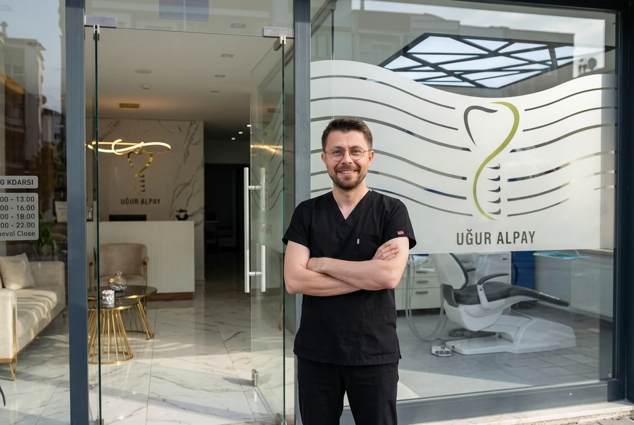 Dt. Mehmet Uğur Alpay klinik girişinde, cam kapıda klinik logosu